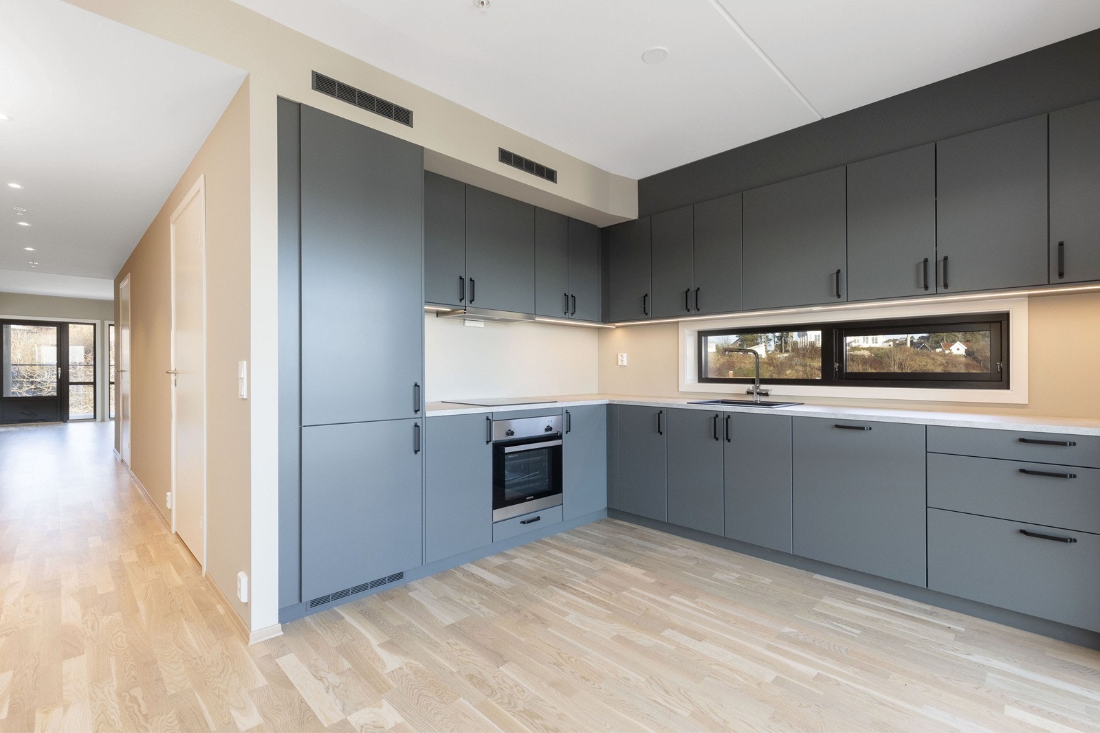 Moderne Sigdal kjøkkeninnredning med høyskap og integrerte hvitevarer. Galleribilde