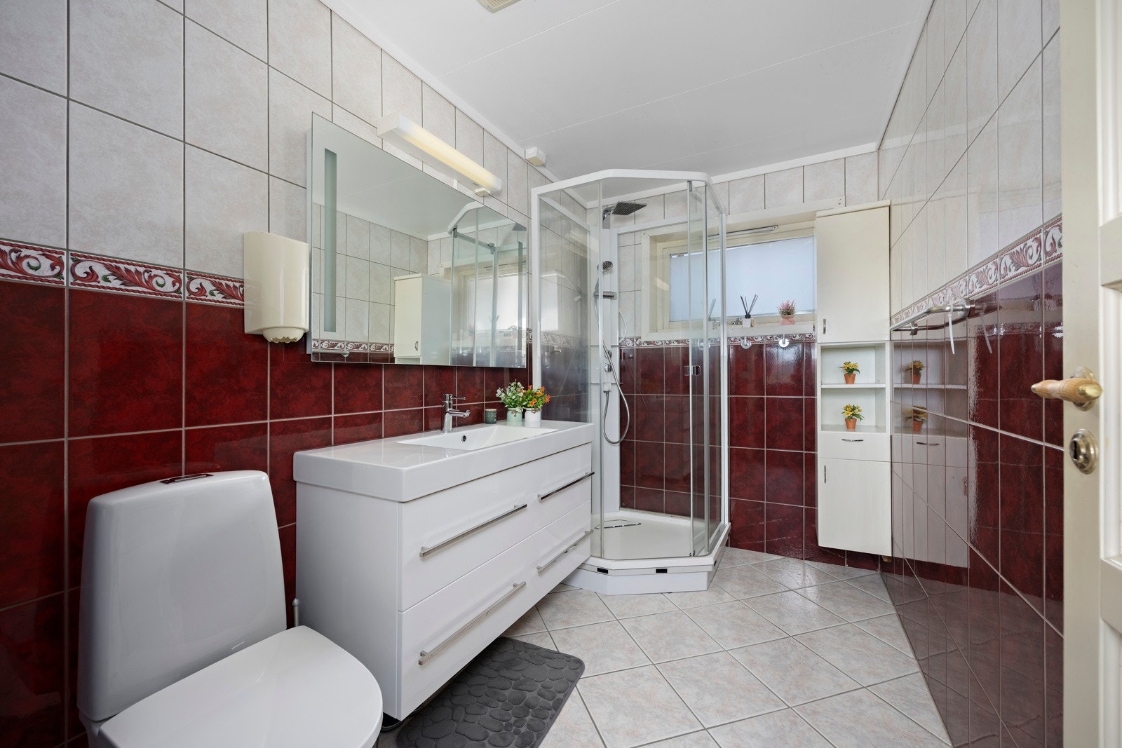 Bad innredet med dusj kabinett, gulvmontert toalett og innredning med nedsunket servant med speil Galleribilde