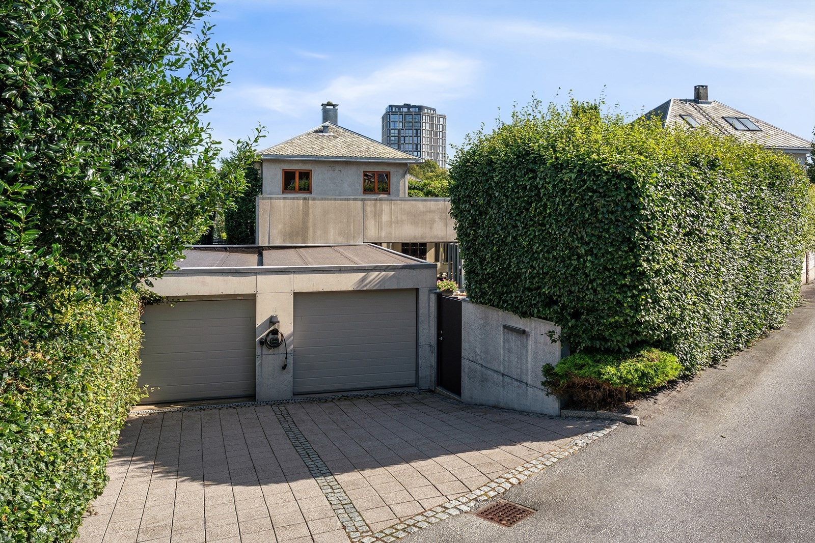 Dobbel garasje/carport med gårdsrom for to biler til. Brosteinsdetaljer rundt heller. Port ved begge inngangsider. Galleribilde