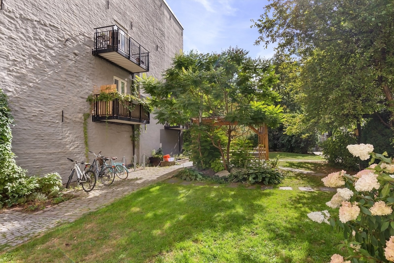 Bakgården er opparbeidet med brostein, plen og beplantning. Galleribilde