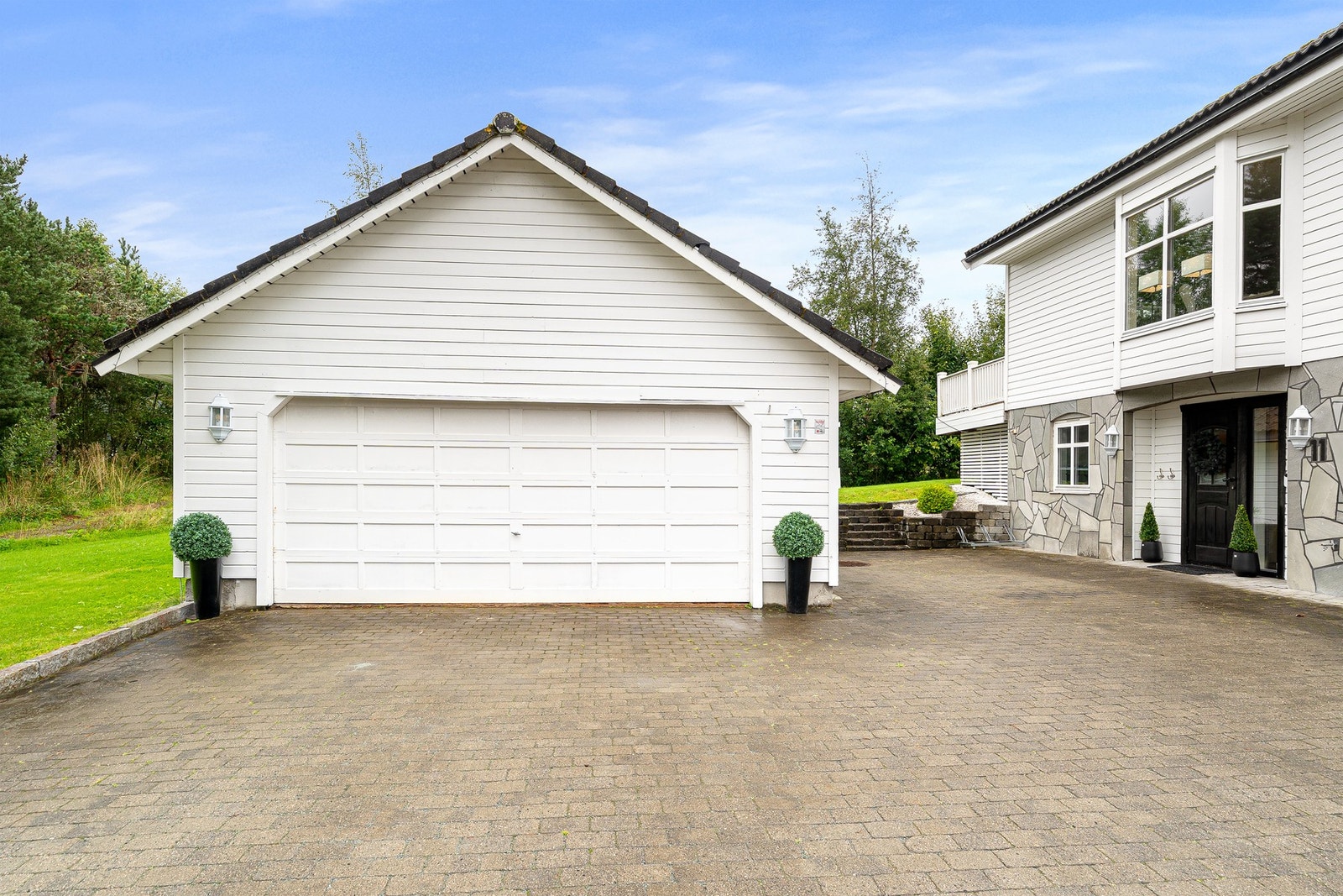 Stor steinlagt gårdsplass med en stor dobbelgarasje Galleribilde
