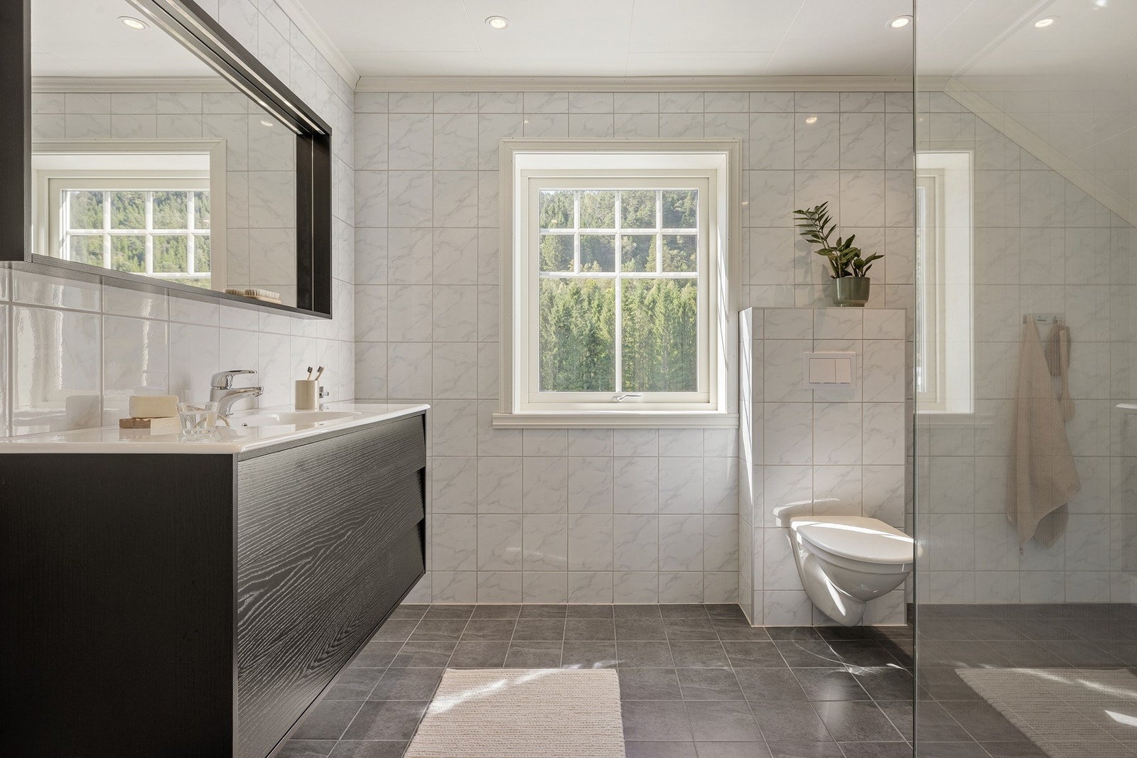 Badet er helfliset med dusjhjørne, toalett og baderomsinnredning. Galleribilde