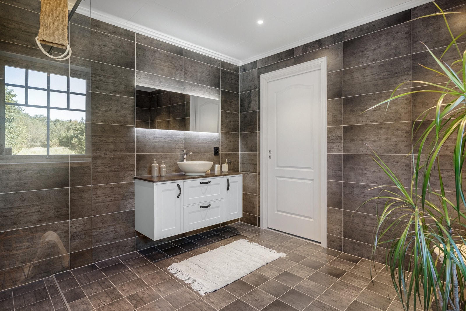 Det er innredet med badekar, dusjhjørne, toalett og servant med oppbevaring. Galleribilde