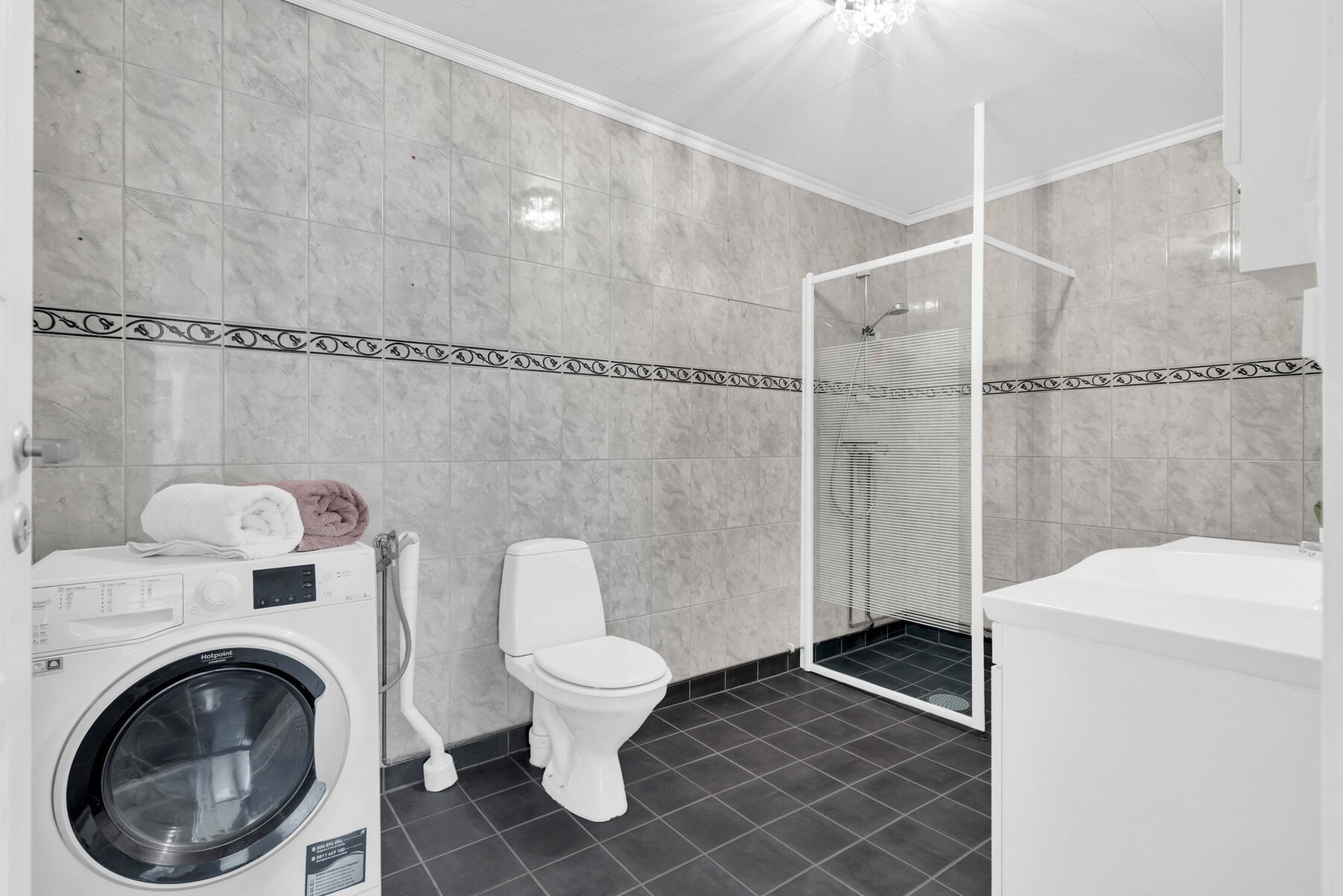 Rommet er innredet med vegghengt servantskap med heldekkende servant, overskap og speil med overlys, gulvmontert toalett og dusjnisje med glassvegg. Her finnes også opplegg og plass til vaskemaskin, noe som gjør rommet svært praktisk i hverdagen. Galleribilde