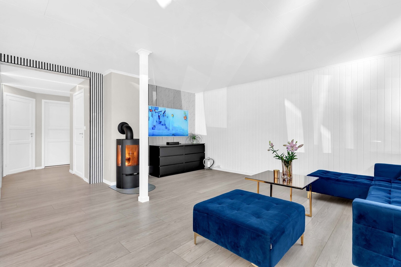 Den åpne løsningen mot kjøkkenet skaper en sosial atmosfære, mens vedovnen gir lun varme på kalde vinterkvelder. Galleribilde