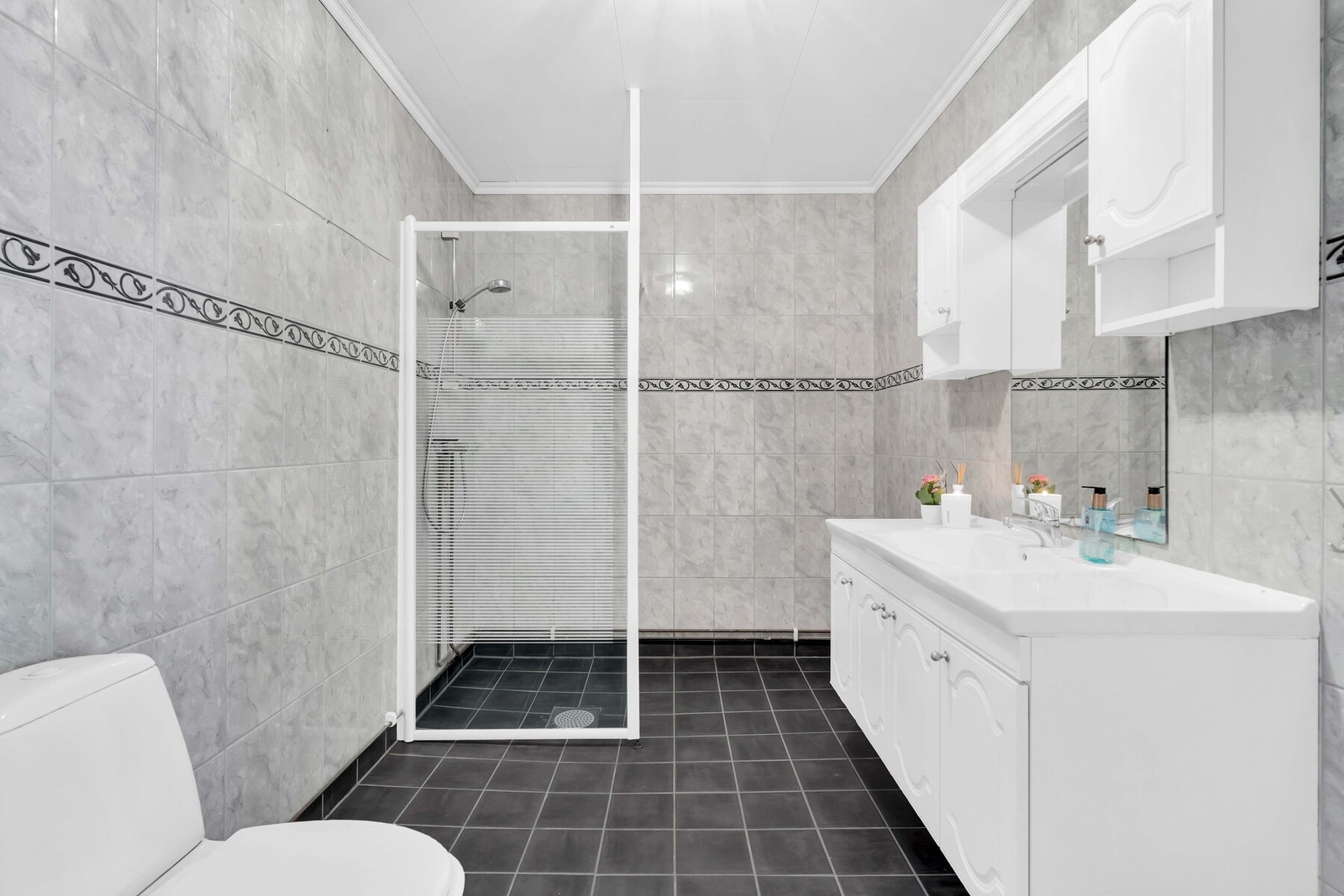 Badet er fra byggeår (2000) og fremstår som lyst og funksjonelt med fliser på både gulv og vegger. Det er installert elektrisk gulvvarme som gir en behagelig varme året rundt. Galleribilde