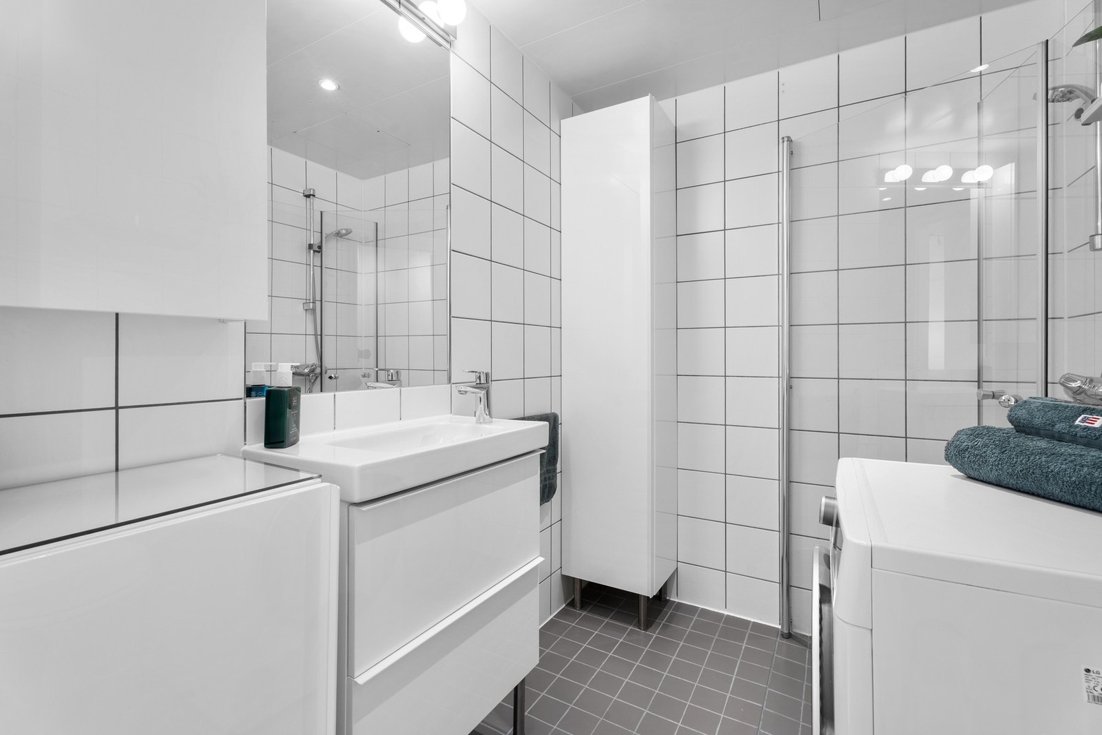 Badet består av lyse fliser, varme i gulv og spesielt mye oppbevaringsplass. Galleribilde