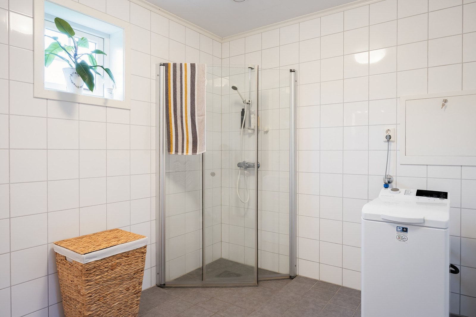 Badet er innredet med dusjvegger av glass, vegghengt toalett, servant med underskap, speil med lys, samt opplegg for vaskemaskin. Galleribilde