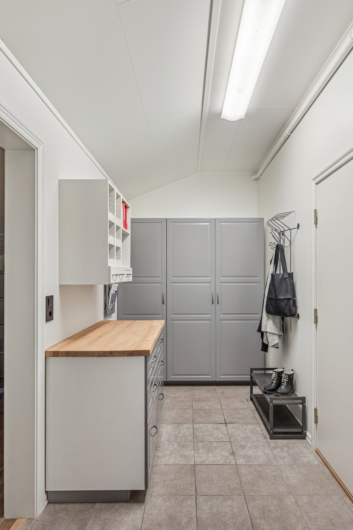 Gangen mellom bolig og garasje er utstyrt med gode oppbevaringsløsninger, benkeplass og garderobeskap. Herfra er det tilgang til to fullisolerte boder, samt tilgang til garasjen. Galleribilde