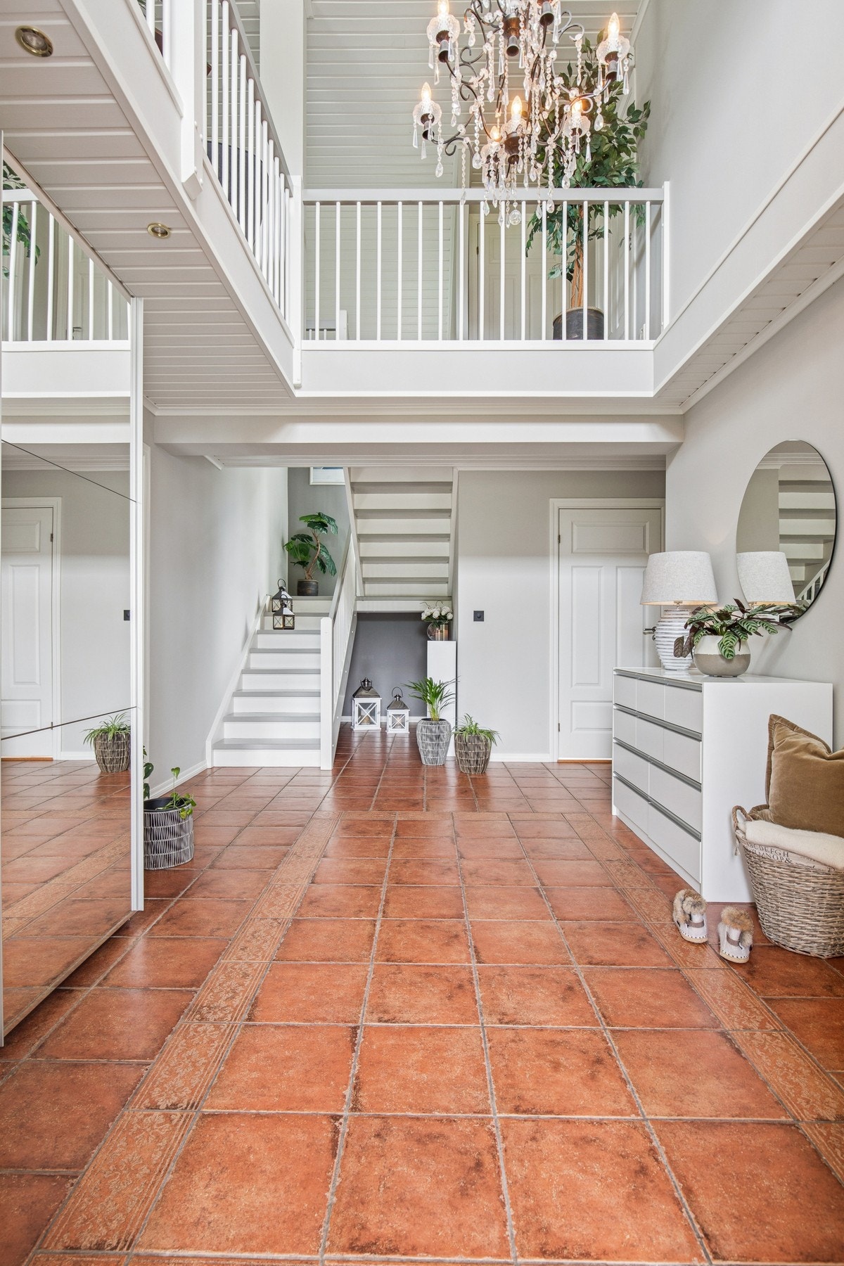 Imponerende hall med åpen himling, flislagt gulv med varmekabler og trapp opp til boligens andre etasje. Galleribilde