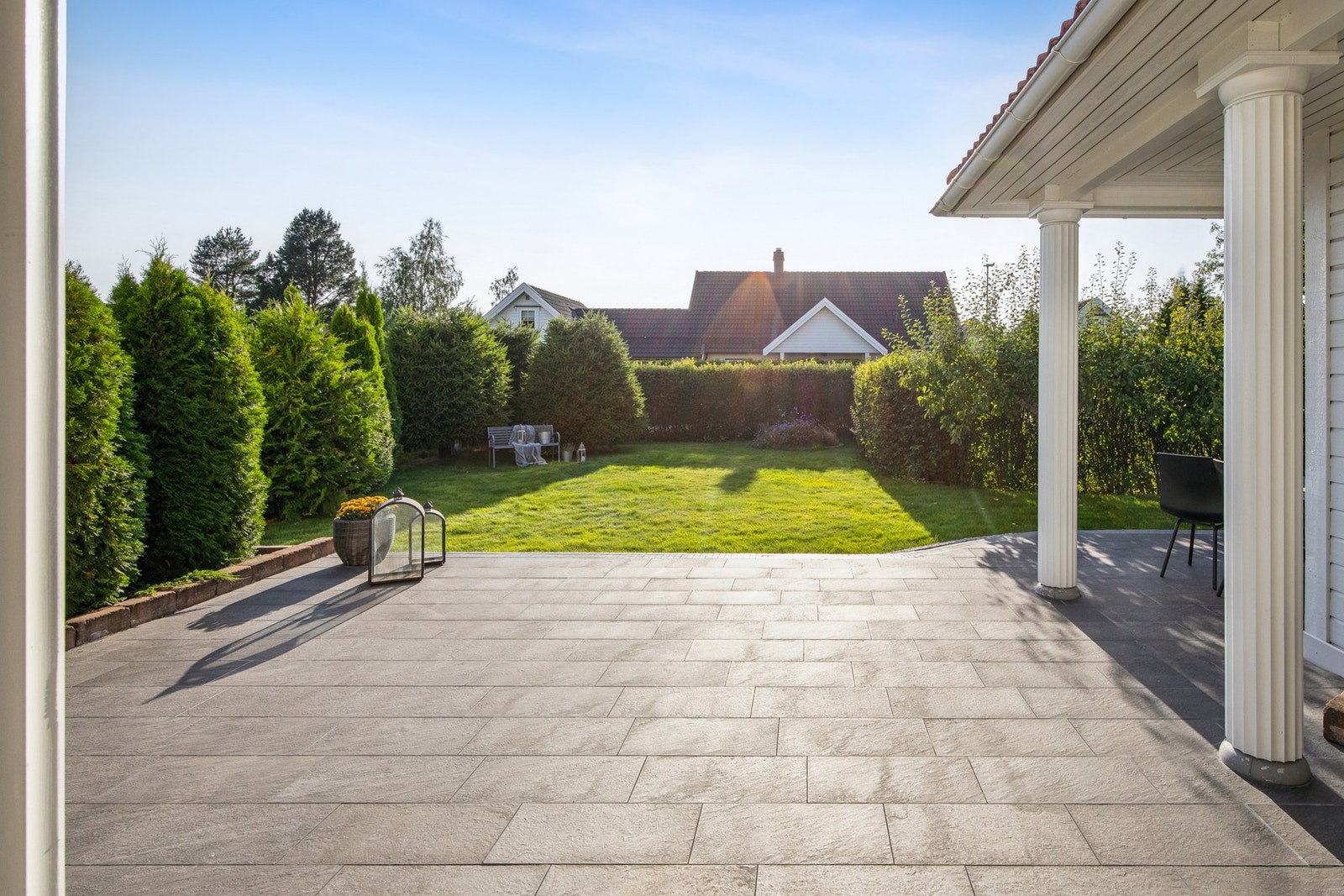 Vestvendt, flislagt terrasse med god plass til utemøbler og trivelig hage med plen og beplantning. Galleribilde