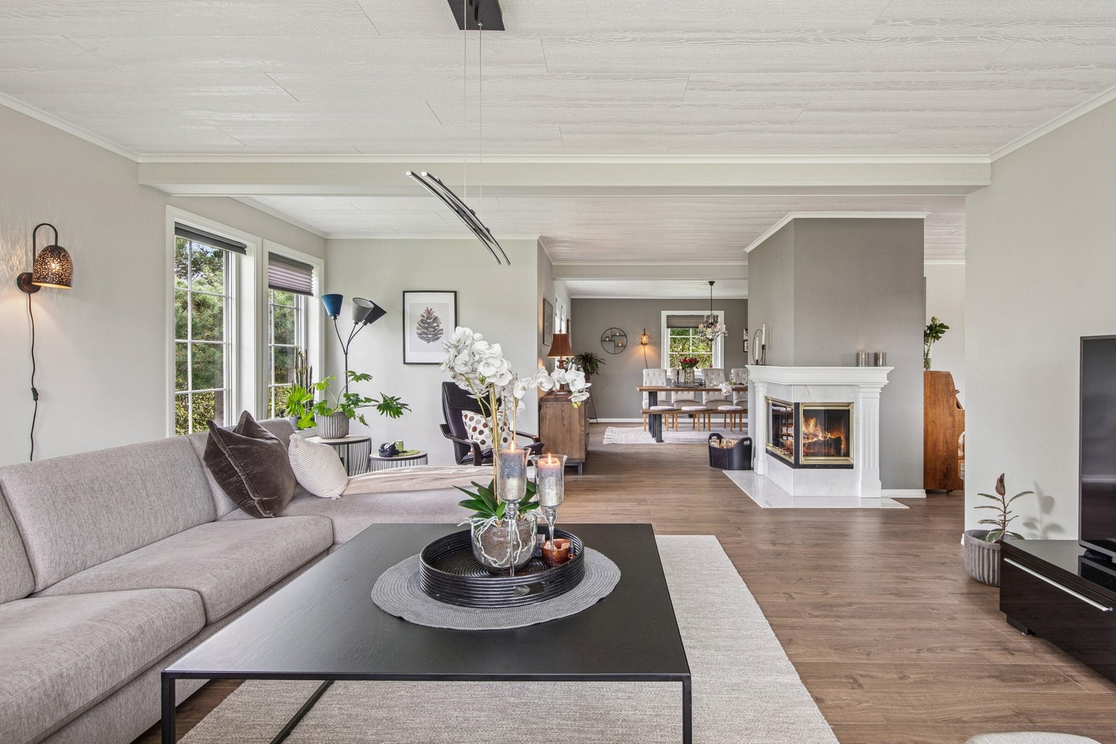 Stuen åpner seg opp mot en romslig spisestue, der peisen står som et naturlig midtpunkt mellom sonene. Galleribilde