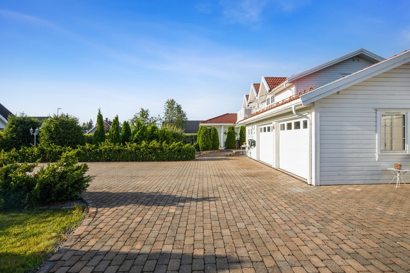 Eiendommen har en romslig dobbelgarasje med elektriske porter som gir trygg og enkel parkering året rundt. I tillegg er det en stor, steinlagt gårdsplass med svært gode parkeringsmuligheter for flere biler Galleribilde