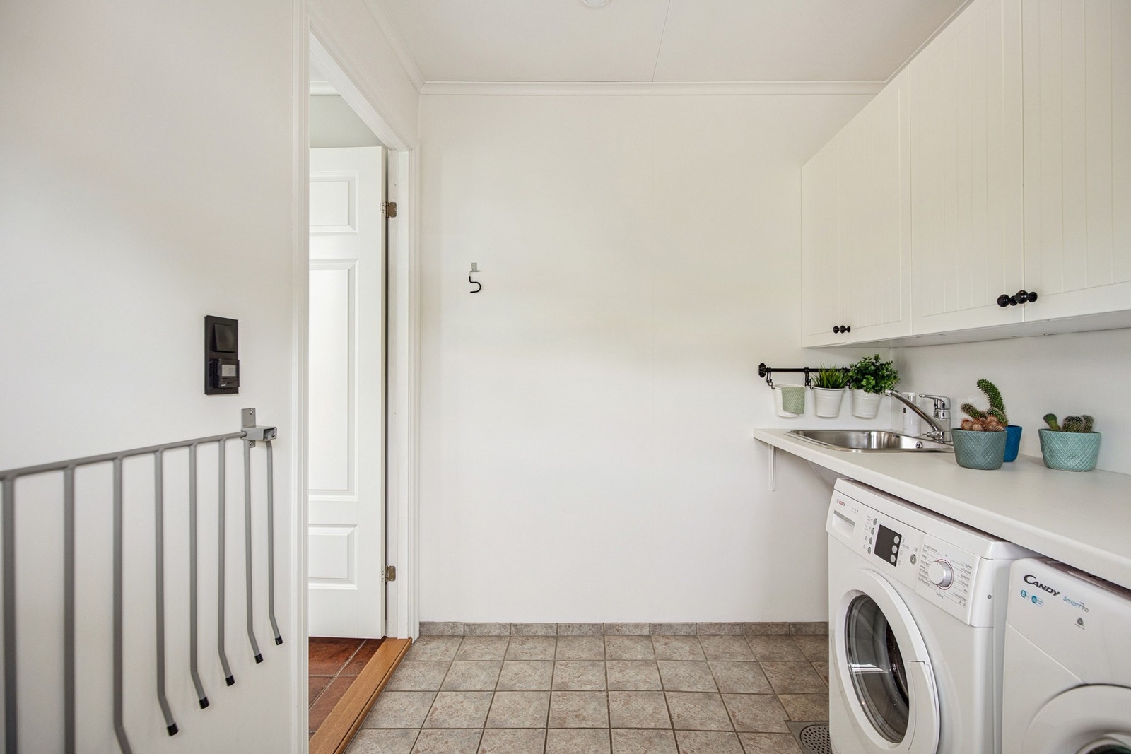 Vaskerommet er praktisk innredet med arbeidsbenk, utslagsvask og plass til både vaskemaskin og tørketrommel. Et funksjonelt rom som gjør hverdagen enklere. Galleribilde