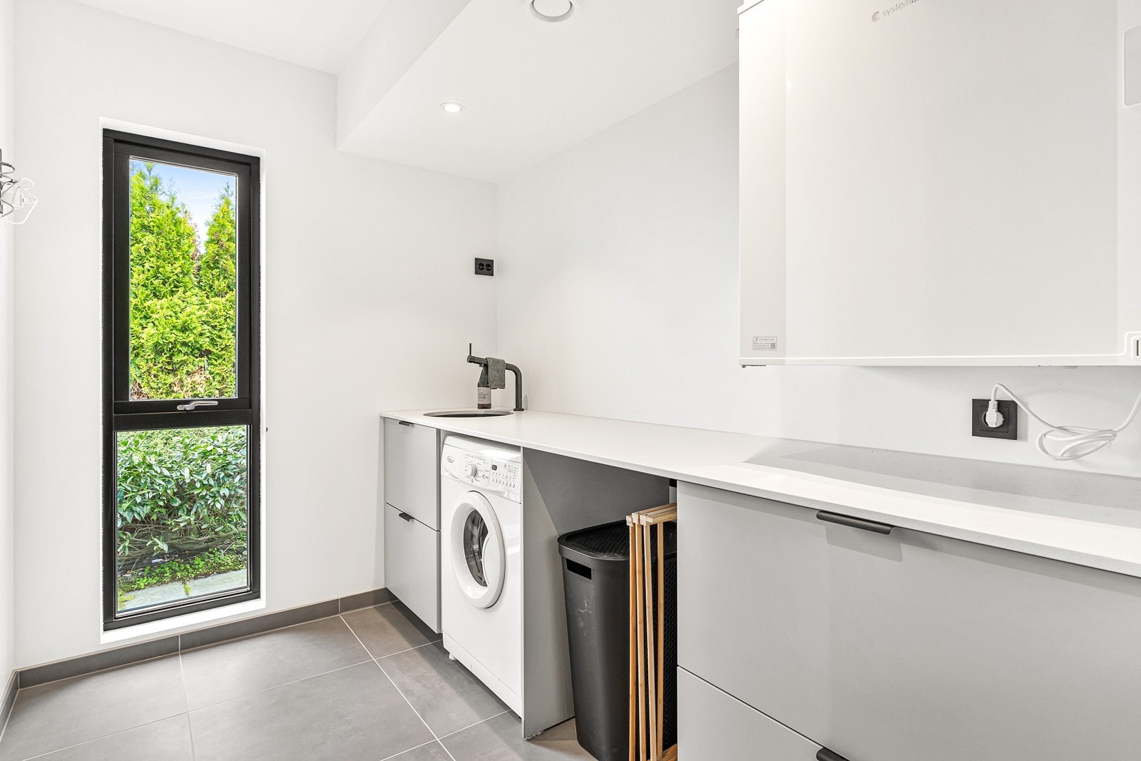 - Separat vaskerom med fliser på gulv og praktisk vaskeromsinnredning fra IKEA med benkeplate i glasskompositt fra Nerostein - Galleribilde