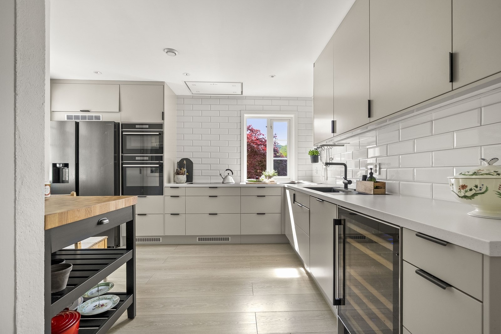 Lekkert kjøkken med integrert steikeovn, kombiovn micro/steikeovn, 80 cm induksjonstopp, takventilator, vinskap, side by side kjøl/frys. Galleribilde