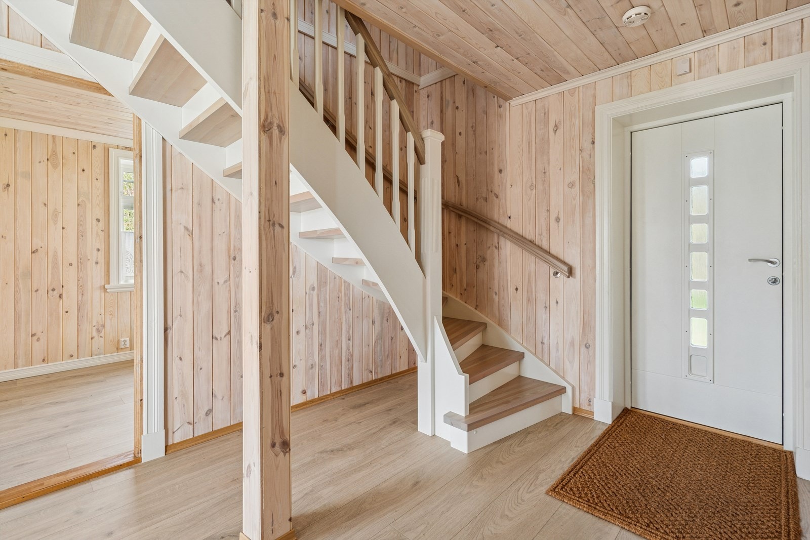 Videre innenfor døren ønsker en lys og hyggelig entré deg velkommen inn. Rommet er pent gjennomført i lyse og moderne panel og byr på god plass til å henge og sette fra seg sko- og yttertøy. Galleribilde