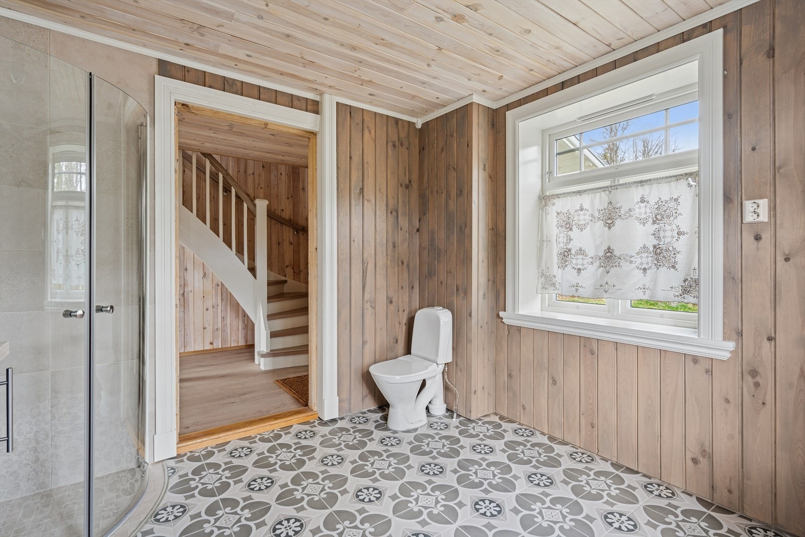 Rommet er pent gjennomført med flislagt gulv og dusjone, samt beiset panel på øvrige vegger. Det er pene mønstrede fliser på gulvet som kler huset øvrige utførelse særdeles godt med gulvvarme. Galleribilde