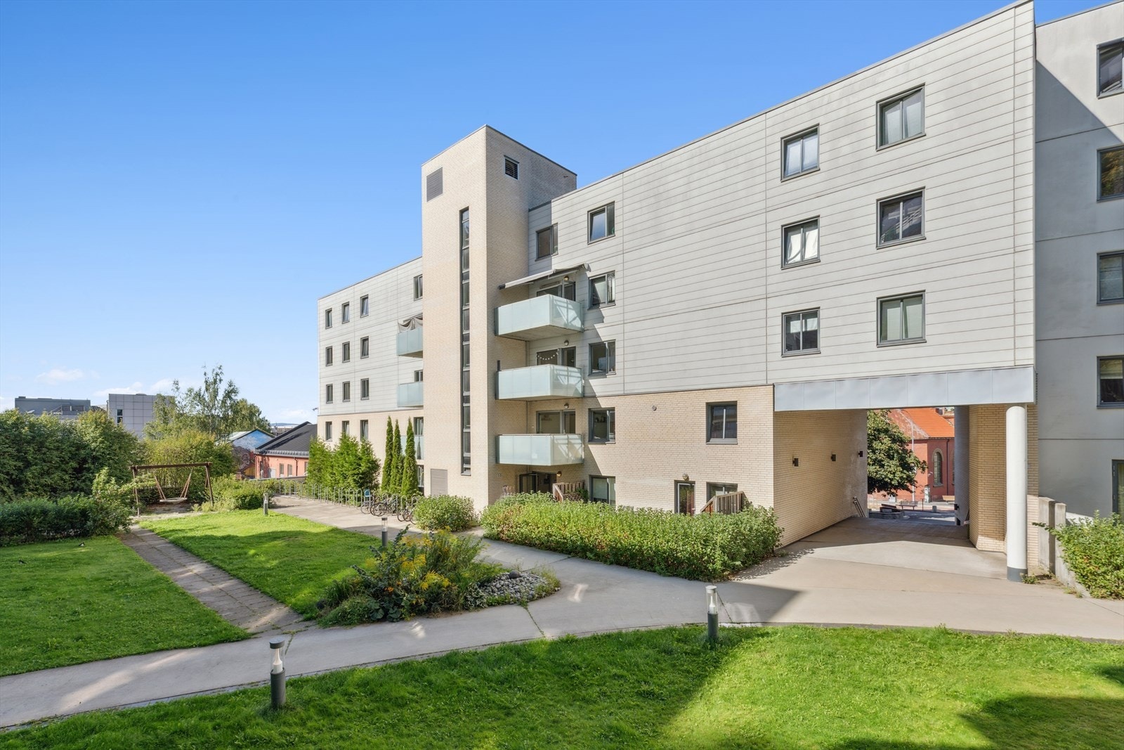 Bakgårdsarealet er pent opparbeidet med stikkveier til inngangspartiene samt pent buskebeplantning langs fasadene. Galleribilde