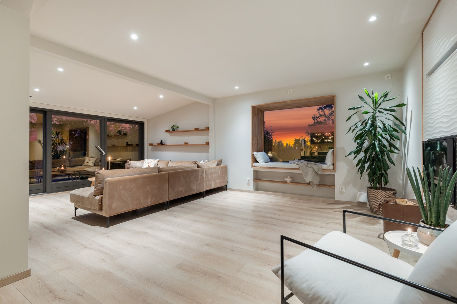 Innbydende stue med laminatgulv og slette, hvitmalte flater på vegger og i himling Galleribilde