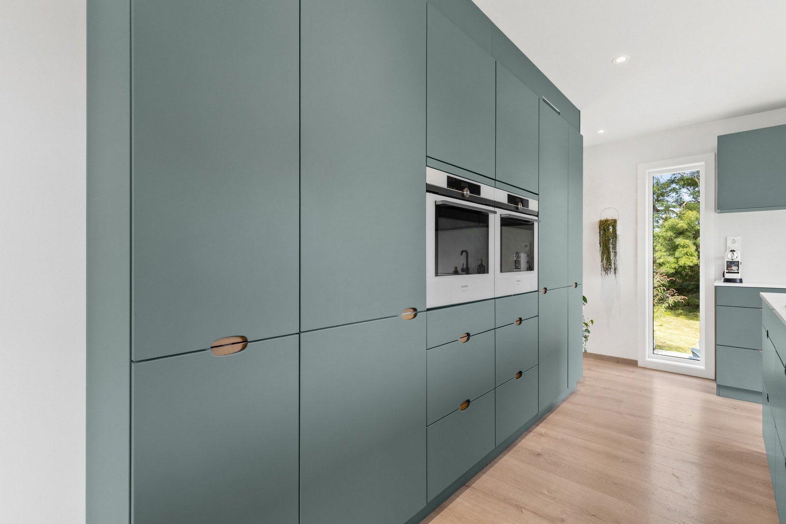 Kjøkkenet er fullt utstyrt med integrerte hvitevarer som kjøleskap, fryseskap, oppvaskmaskin, platetopp og to stekeovner ved siden av hverandre Galleribilde