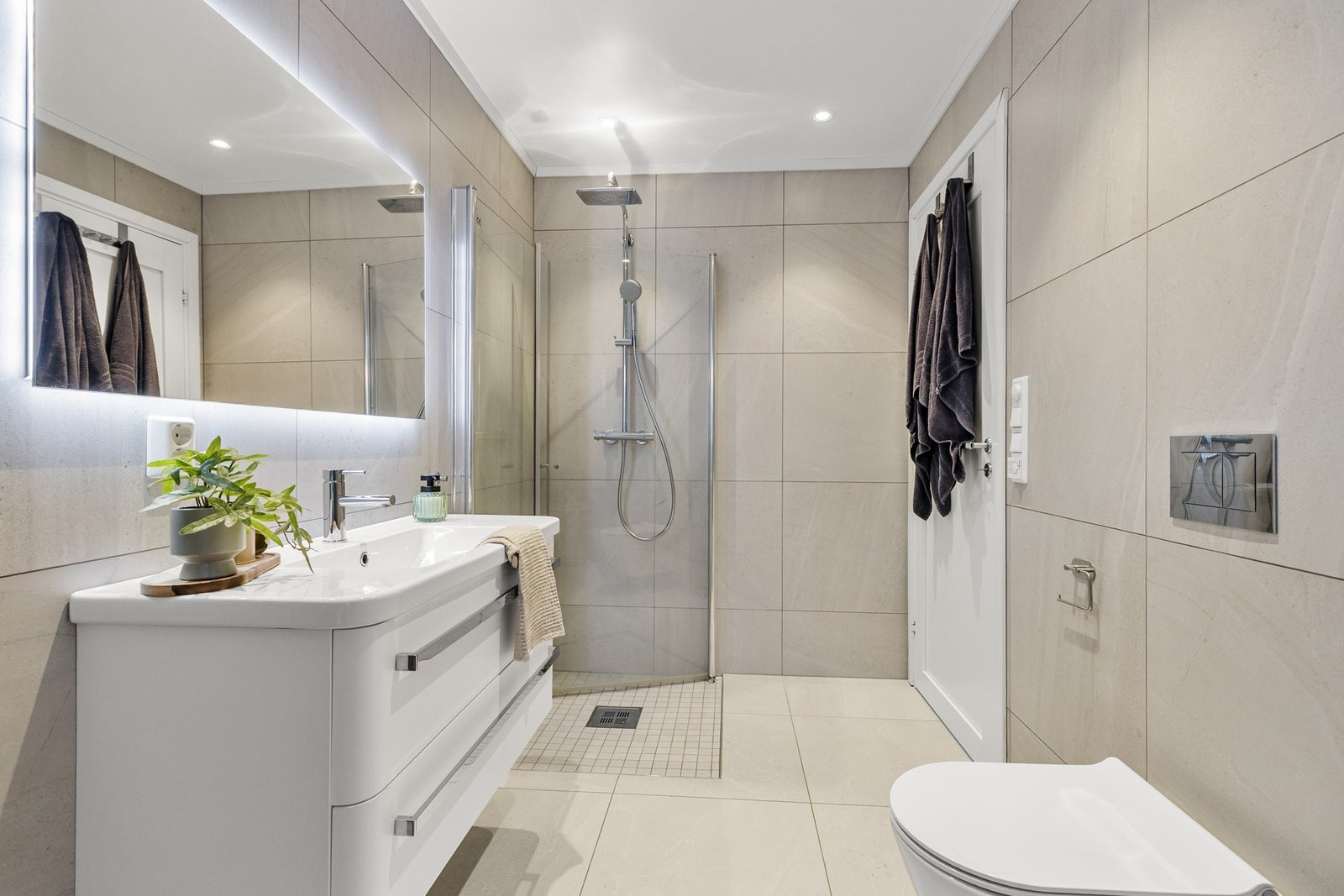 Rommet har innredning med nedfelt servant, veggmontert toalett, dusjhjørne, varmtvannsbereder og opplegg for vaskemaskin Galleribilde