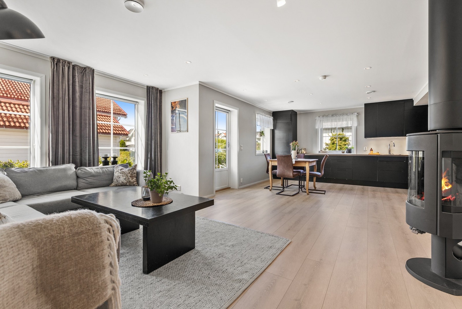 Lys og innbydende stue med 1-stavs laminatgulv, slette flater på vegger og downlights i himling Galleribilde