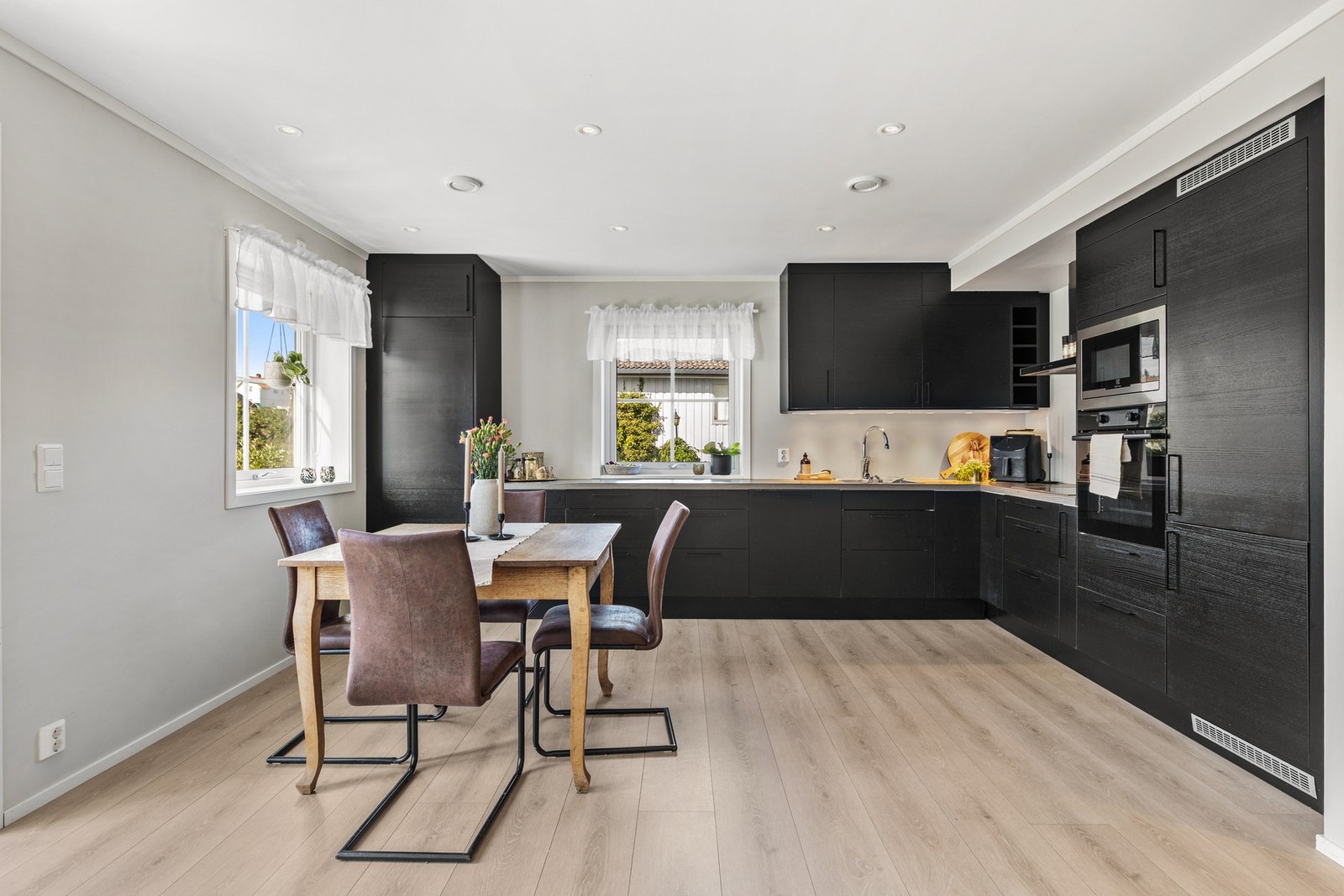 Stilren kjøkkeninnredning med glatte fronter og laminert benkeplate med vaskekum i stål Galleribilde