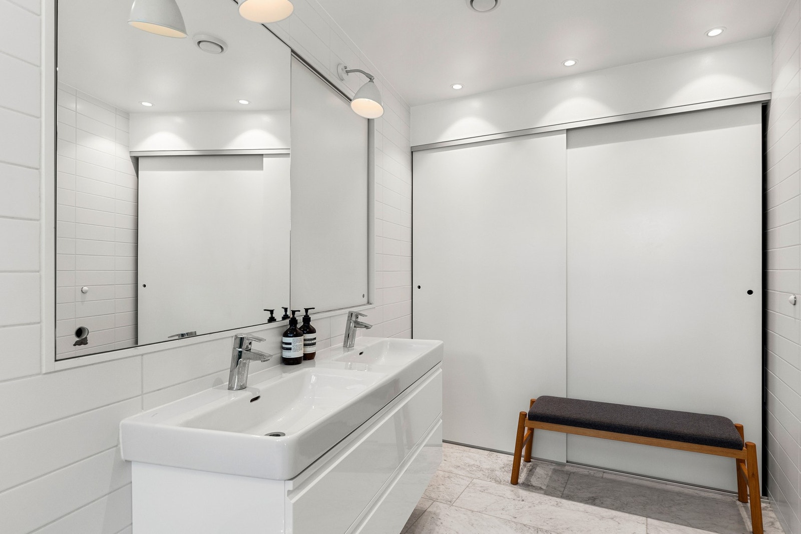 Lekkert bad med gulvvarme og flislagte overflater. Oppbevaring i skap med skyvedører. Galleribilde