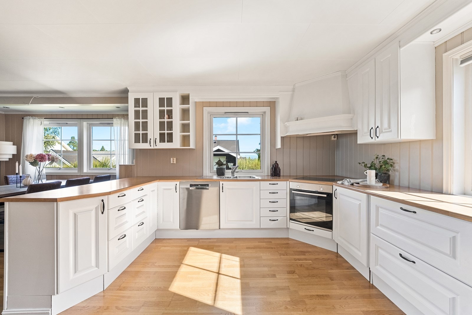 Boligen har et stort kjøkken med lys innredning og god skap- og benkeplass med åpning til stue og spisestue. Galleribilde