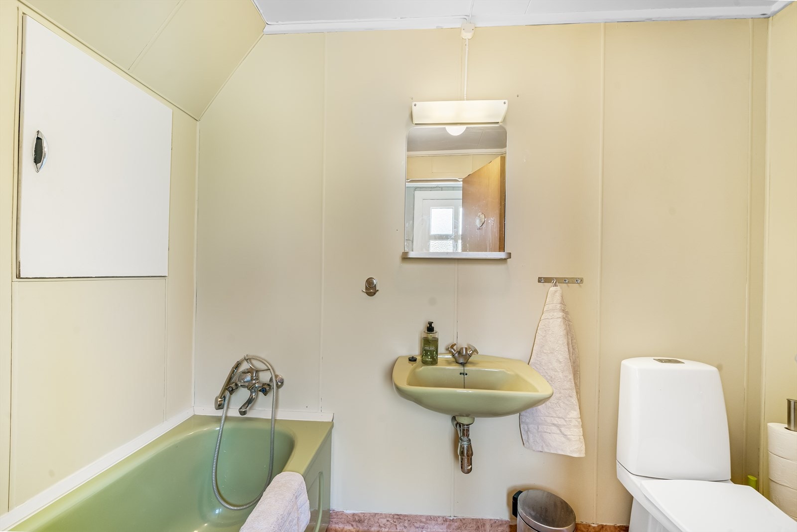 Eldre bad med badekar og toalett. Luke i vegg til lagring. Galleribilde