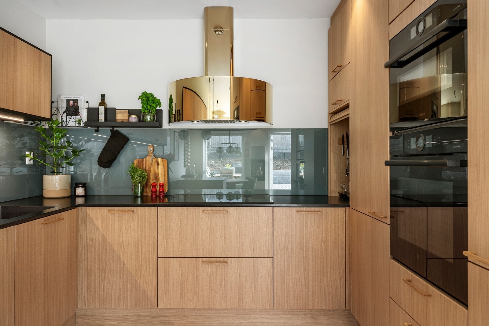 Moderne uttrykk med fronter i treutførelse, glassplate over vasken, samt benkeplate i stein som tåler direkte varme og mye slitasje. Galleribilde