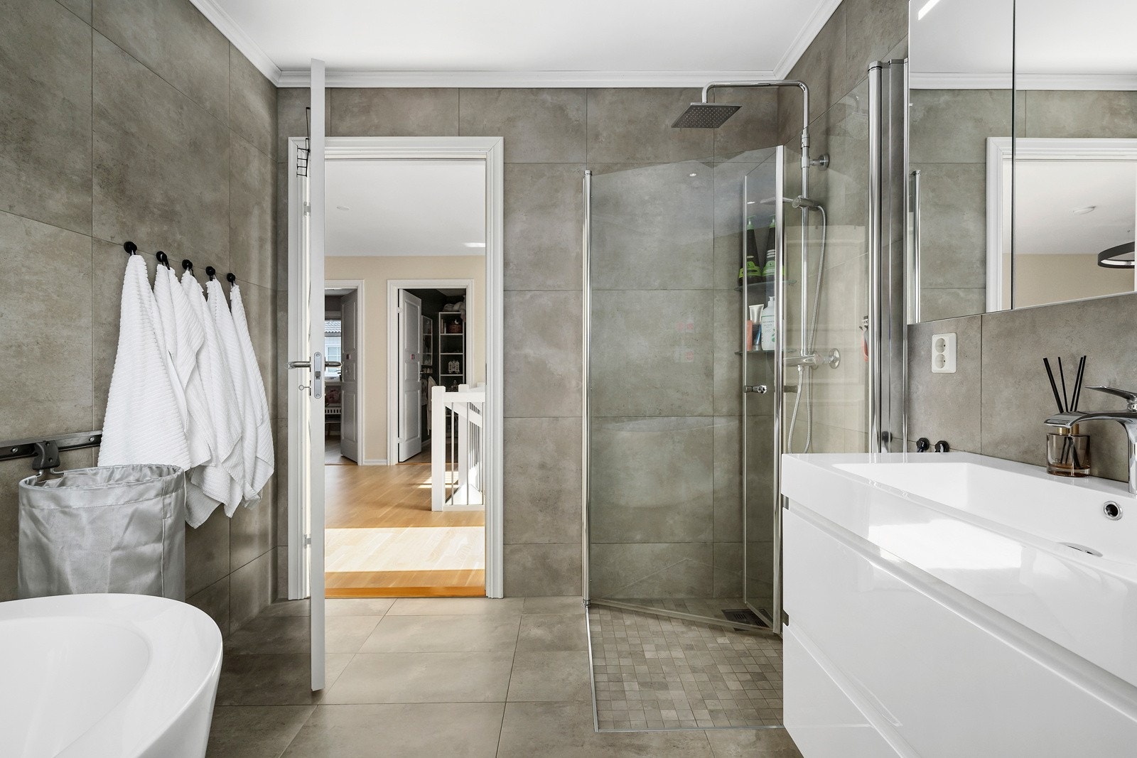 Et delikat innredet bad med store fliser, gulvvarme, downlights og balansert ventilasjon. Galleribilde