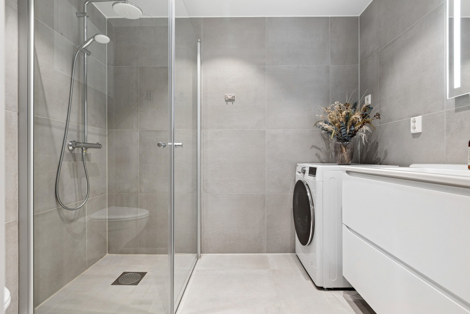 Lekkert baderom på 4,5 kvm med store, moderne fliser som gir et tidløst uttrykk. Galleribilde