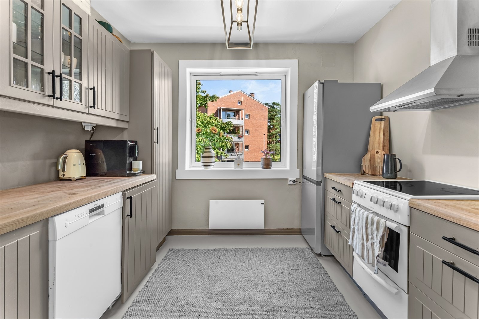 Hyggelig separat kjøkken, utstyrt med malt profilert kjøkkeninnredning, heltre benkeplate, malte flater over benk, utslagsvask med blandebatteri, kjøkkenventilator og opplegg for oppvaskmaskin. Galleribilde