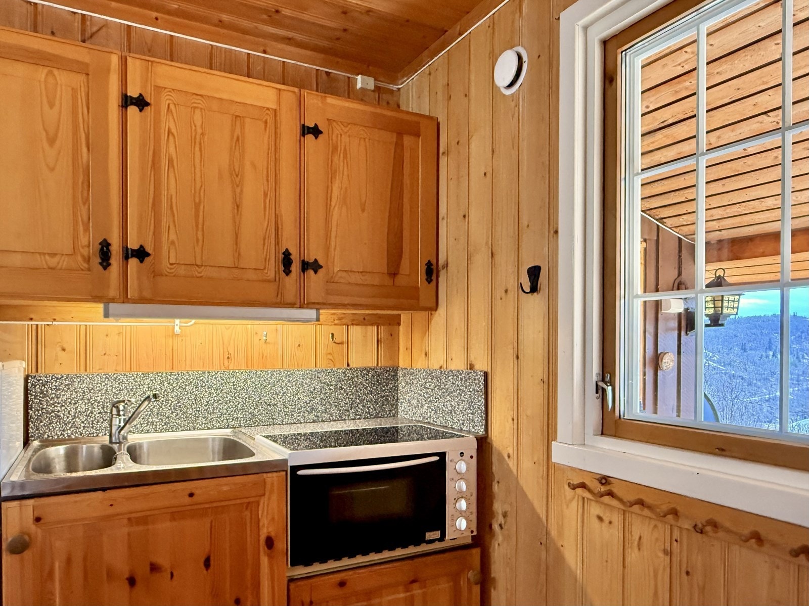 Her er det innredning fra byggeår med furuskaper med furu fyllingsdører med profiler. På den ene veggen er det montert stålvask med to kummer og for øvrig benkeplater av laminat. Galleribilde