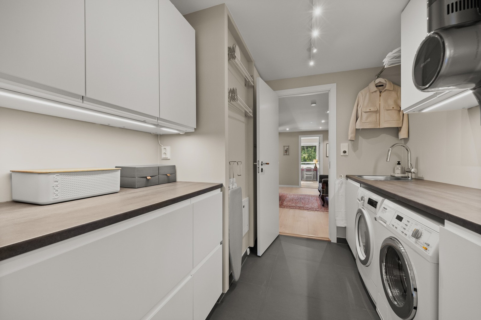 Vaskerom/grovkjøkken med rikelig skap- og benkeplass samt mulighet for integrering av vaskemaskin og tørketrommel. Galleribilde