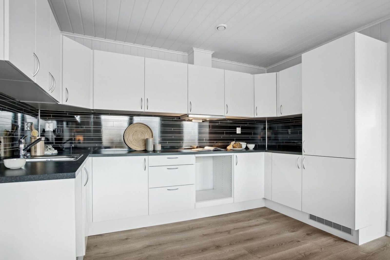 Kjøkkeninnredning fra Aubo med hvite fronter, laminat benkeplate og kitchenboard mellom skapene. Galleribilde