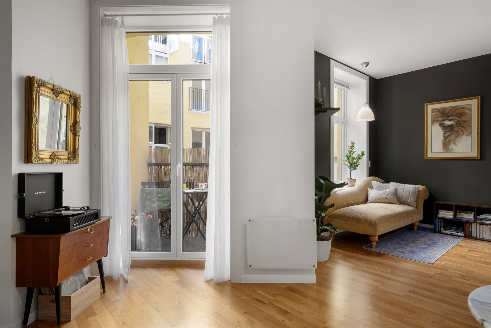 Leiligheten har en åpen stue/kjøkkenløsning med stort vindu og doble balkongdører som skaper et lyst og luftig rom Galleribilde