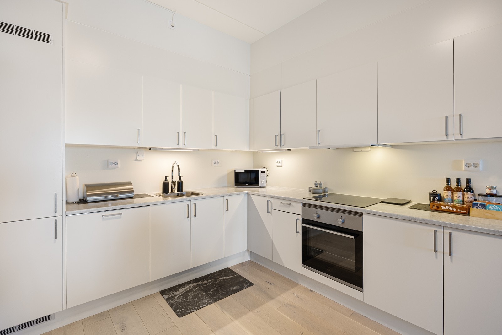 Innredningen er oppforet og har hvite, glatte fronter og laminatbenkeplate med oppvaskkum av metall. Galleribilde