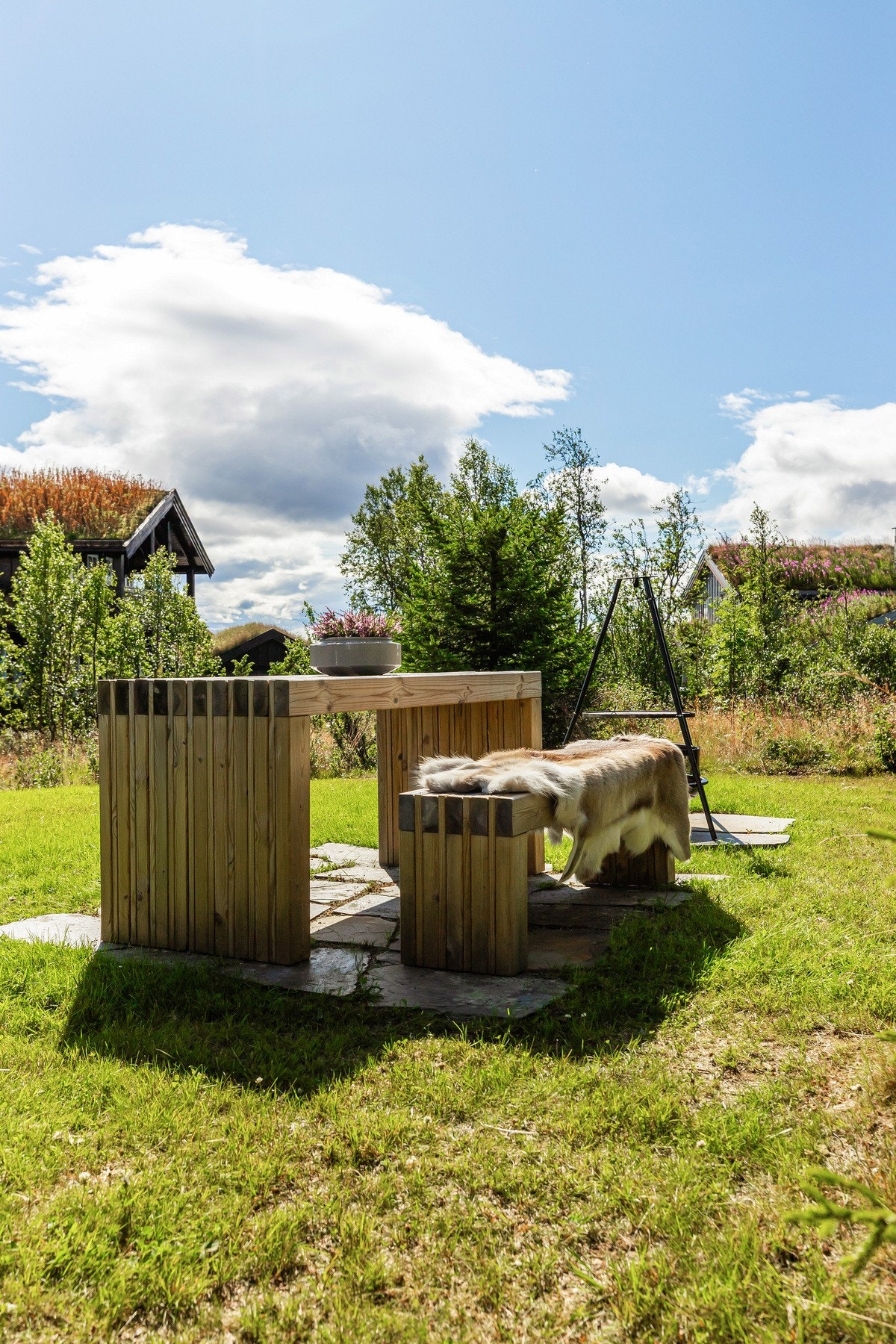 Rundt hytta er det pent oppabeidet med gressarealer og flere utesoner Galleribilde