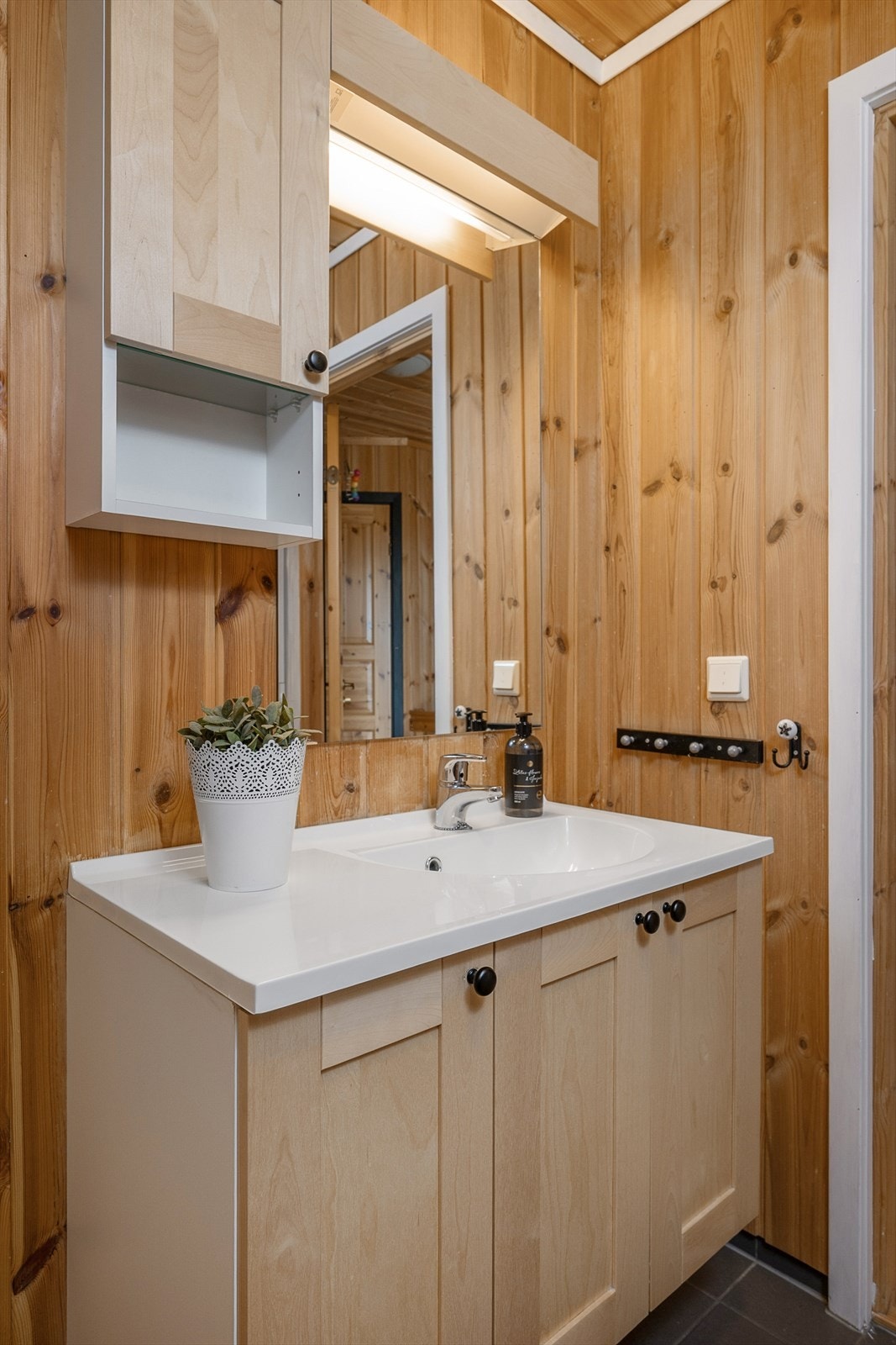 Servantinnredningen har skap for oppbevaring. Panel på vegger og i tak. Fliser på gulv. Galleribilde