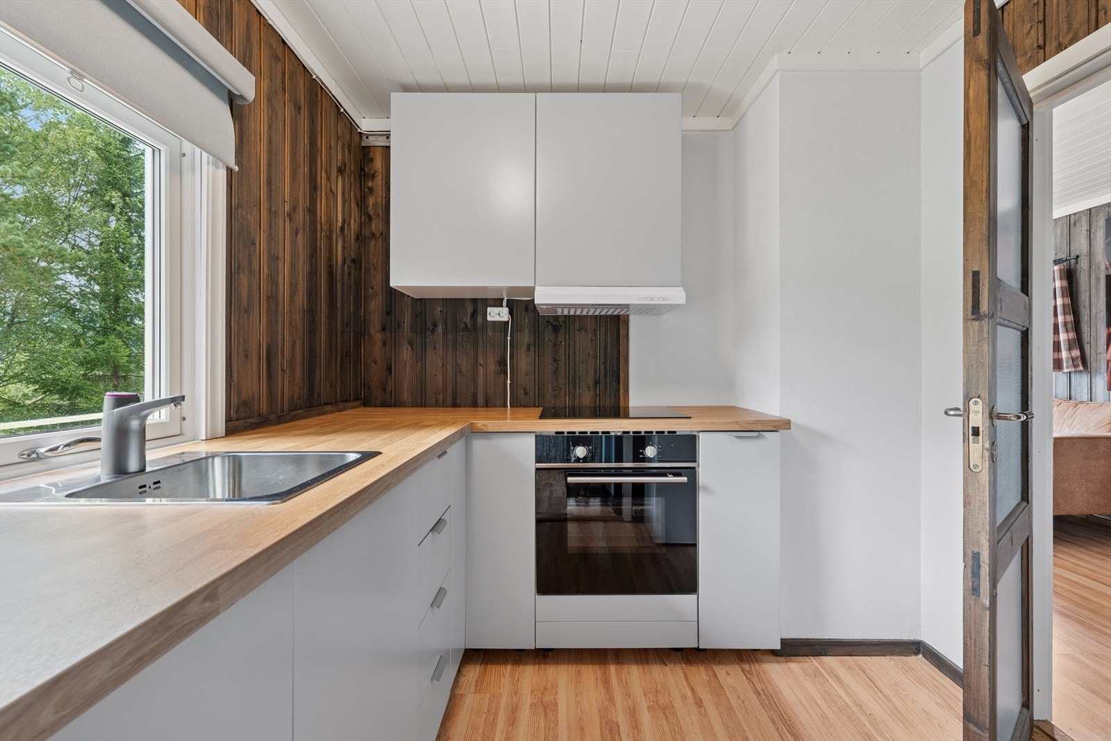 Kjøkkeninnredning fra 2024 med integrert stekeovn og platetopp. Det er montert kum med elektrisk vannkran som kan kobles til vannkanne under benken. Galleribilde