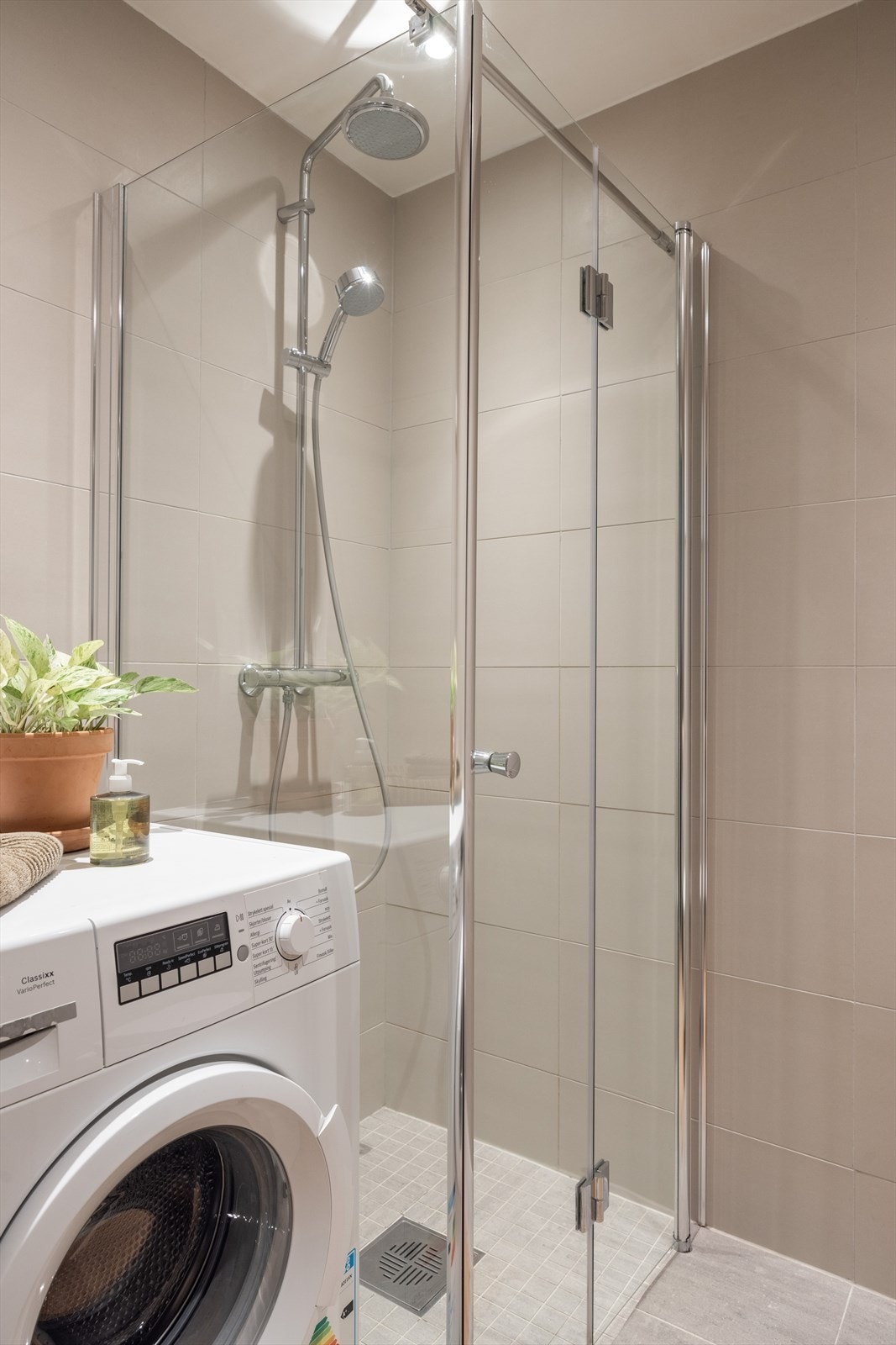 Dusjhjørne med svingbare glassdører og opplegg for vaskemaskin. Galleribilde