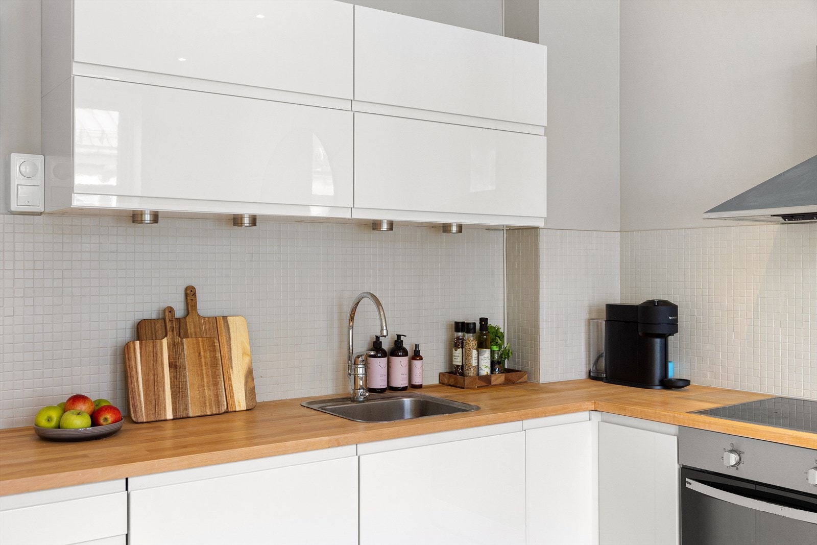 Innredningen består av både over- og underskap, med belysning under overskapene og mosaikkfliser mellom benkeplate og overskap. Galleribilde