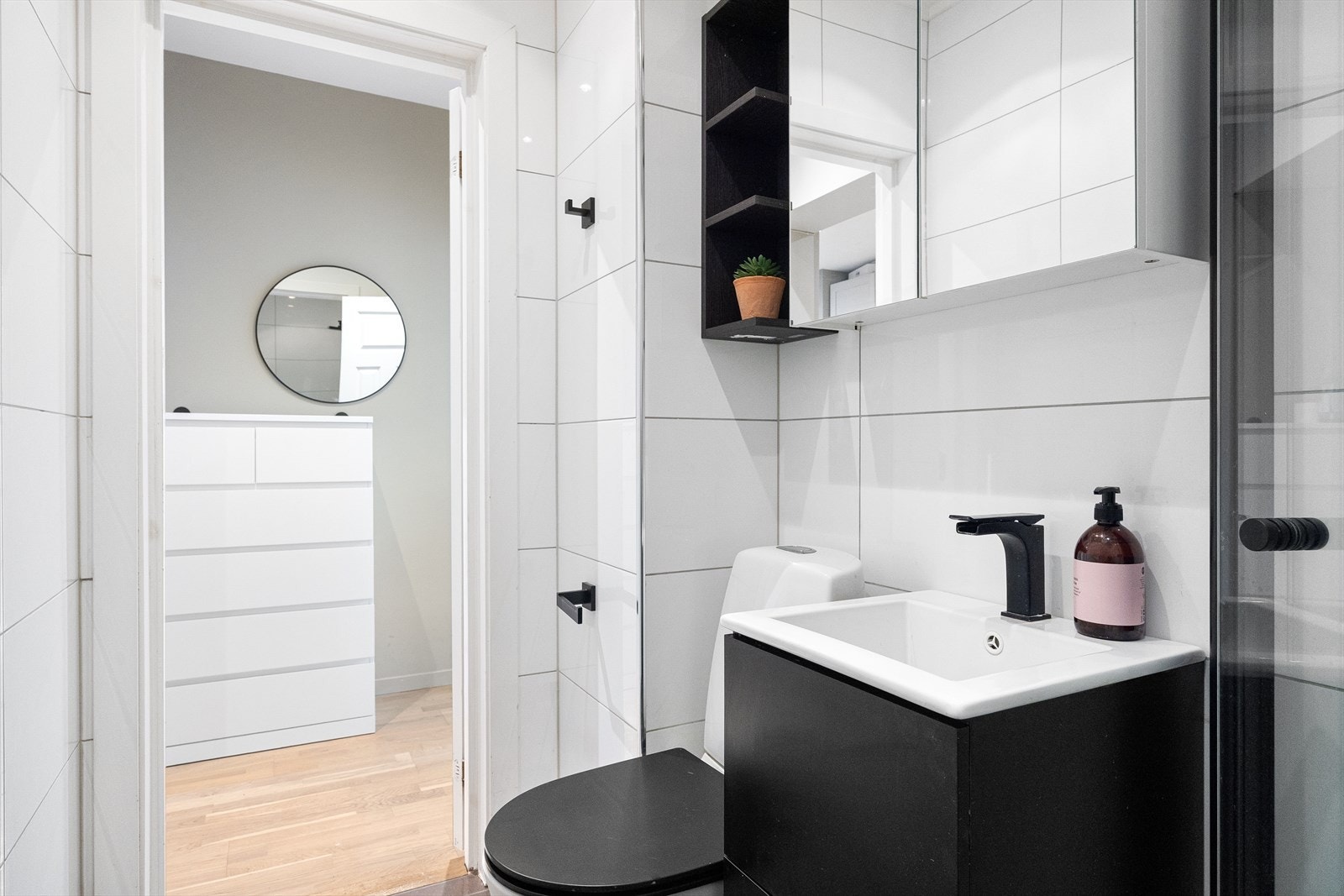 Badet har servantskap med nedfelt servant, veggskap med speildører og belysning, gulvmontert klosett samt dusjsone med foldedør i herdet glass. Galleribilde