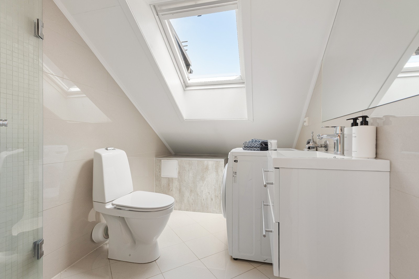 Lekkert flislagt bad med gulvvarme og opplegg for vaskemaskin Galleribilde