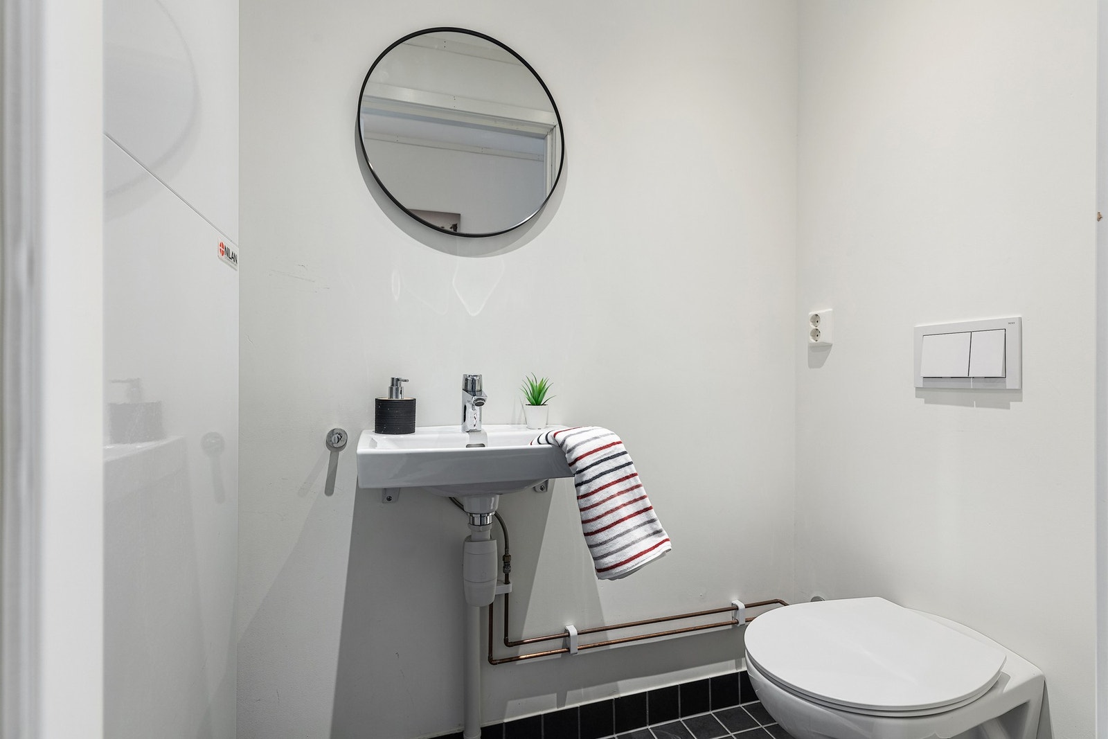 Første etasje har et praktisk toalettrom med flislagt gulv, vegghengt toalett og servant Galleribilde