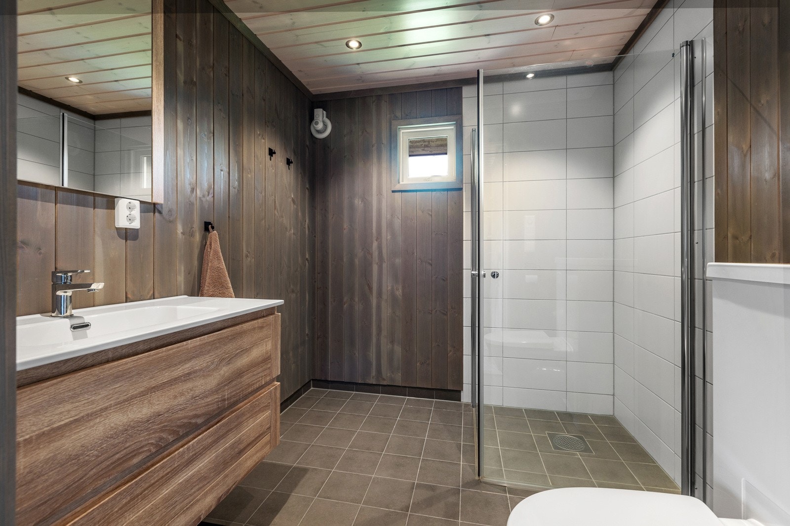 Badet har fliser på gulvet og i dusjsonen, mens de andre veggene og taket er kledd med panel. Galleribilde