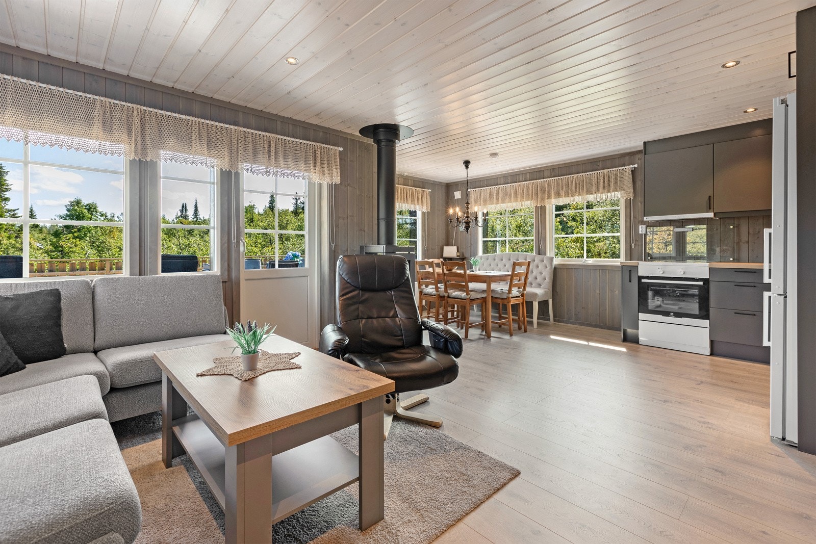Store vinduer slipper inn rikelig med naturlig lys, og den åpne løsningen mot kjøkkenet gjør stuen både romslig og sosial. Galleribilde